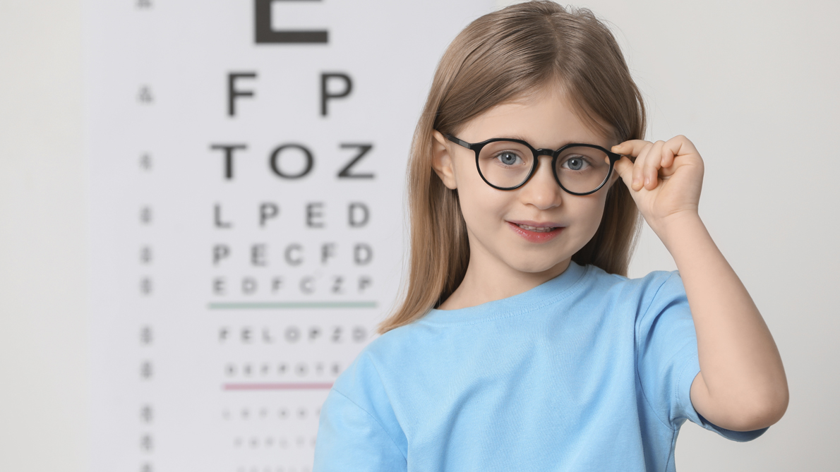 Little girl with glasses against vision test chart